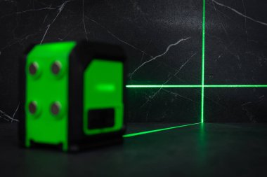 Bloklardan bir duvar inşa ederken lazer seviyesi. İnşaat alanlarındaki hatları ve seviyeleri belirlemek için lazer seviyesi tamamlanmamış beton bloklardan yapılmış bir duvarın üzerinde duruyor..