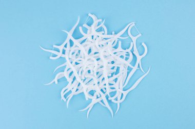 Mavi arka planda diş ipiyle plastik beyaz diş kürdanı.