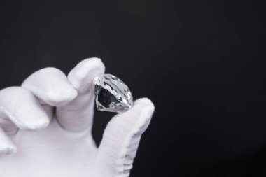 Mücevher aletleriyle cilalanmış elmasların değerlendirilmesinde elmas uzmanının ellerinin yakınlaştırılması.