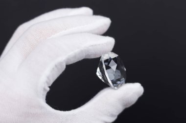 Elmas uzmanı beyaz eldivenli elmasların yakınlaştırılması. Mücevher aletleri kullanılarak parlaklaştırılmış elmasların değerlendirilmesi..