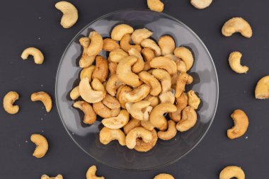 Koyu arkaplanda cam kasede kavrulmuş kaju fıstığı manzarası.