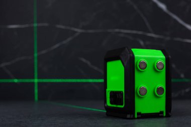 Bloklardan bir duvar inşa ederken lazer seviyesi. İnşaat alanlarındaki hatları ve seviyeleri belirlemek için lazer seviyesi tamamlanmamış beton bloklardan yapılmış bir duvarın üzerinde duruyor..