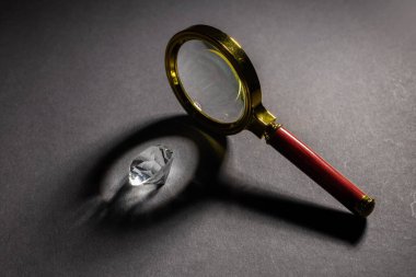 Karanlık yüzeyde duran büyüteçle elmas üzerine düşen ışık demeti.