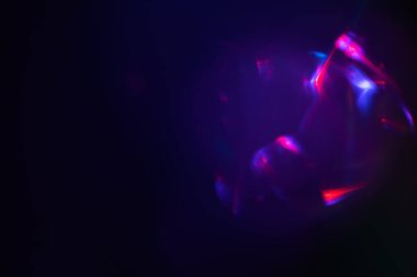 Siyah arkaplanda renkli ışık sızıntısı, uzun mercekte optik mercek parlaması olan soyut tasarım.