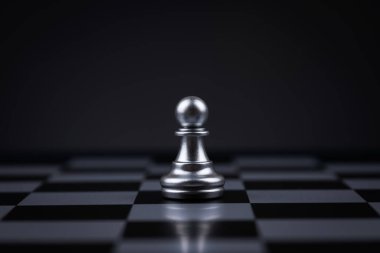 Satranç tahtasındaki bir satranç piyonu karanlık arka planda başarılı iş liderliği kavramı.