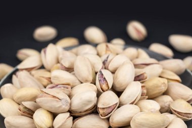 Bira için tuzlu şam fıstığı, Macro, tuzlu fıstıklı biranın siyah arka planında. Sağlıklı Lezzetli Fıstıklar. Tuzlu kavrulmuş fıstık makrosu, rotasyon.