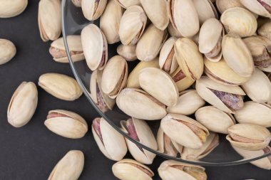 Bira için tuzlu şam fıstığı, Macro, tuzlu fıstıklı biranın siyah arka planında. Sağlıklı Lezzetli Fıstıklar. Tuzlu kavrulmuş fıstık makrosu, rotasyon.