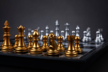 Tahta satranç tahtasına altın ve gümüş satranç figürleri yerleştirildi. İş hayatında entelektüel düello ve taktiksel savaş. Strateji planlaması, liderlik ve takım çalışması kavramı.