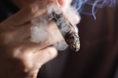 Elinde puro tutan bir adam var.,