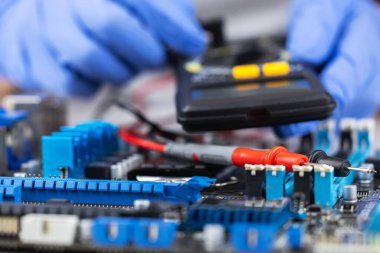 Anakart, sonda ve çokölçer ile test ediliyor, elektronik tanılama sırasında bilgisayar ana kartında sonda kullanan teknisyenlerin yakın çekimi