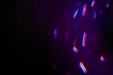 Siyah arkaplanda renkli ışık sızıntısı, uzun mercekte optik mercek parlaması olan soyut tasarım.