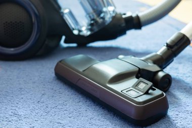 Cleaning carpet with cordless vacuum cleaner indoors.