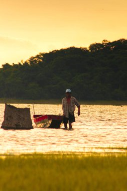 Suda teknesinin yanında duran bir adamın silueti..