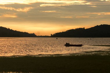 Sudaki bir teknenin silueti ve akşam atmosferi.