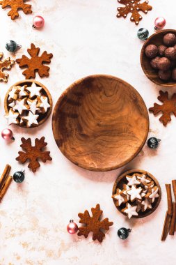 Noel kurabiyeleriyle çevrili boş ahşap tabak. Yıldız şeklinde kurabiyeler, çikolata ve badem, karamelli zencefil. Üst görünüm, alanı kopyala