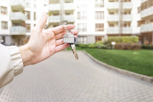 stock image The girl holds a bunch of keys on the background of new buildings. Moving. Buying a home. Mortgage. Raising prices. Accumulation for own housing