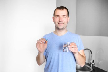 Haplı adam mutfakta su içiyor. Vitaminler. Hastalık. Sağlıksız. Tedavi. Antibiyotikler