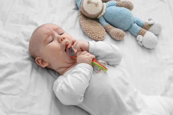 stock image cute baby is playing with a rattle on a white bed. Attention concentration, grasping an object by infants