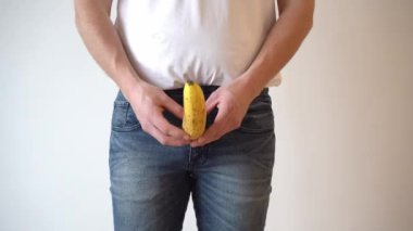 a man holds a banana in the groin area. Problems with the prostate. Age intimate problems of men. Steroids and potency. Passive lifestyle