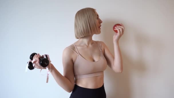 年轻的女运动员拿着哑铃 吃着苹果 在家里运动 在家锻炼 高质量的4K镜头 — 图库视频影像