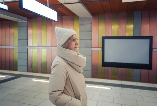 Woman in the subway in winter waiting for transport at the station