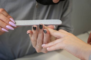 Kuaförde manikür yapma süreci. Kesici. Tırnak cilası, tırnak eti. Çivi törpülenmiş. Tırnak boyama. Tasarım. Sterilizasyon. Manikür, güzellik hizmetleri.