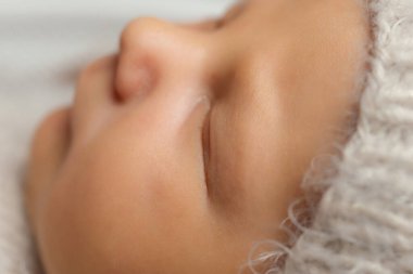 Bej bir takım elbiseyle sepetteki bej halıda uyuyan yeni doğmuş şirin bir bebek. Yüksek kaliteli fotoğraf. Yakın plan.