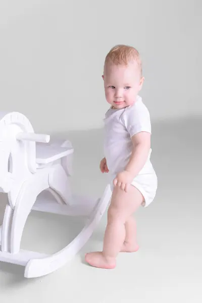 Küçük bir çocuk, bir çocuğun tahta atının yanında duruyor. Mutlu çocukluk kavramı. Yüksek kalite fotoğraf