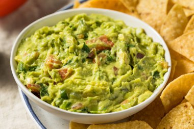 Ev yapımı avokado guacamole ve domatesli tortilla cipsi.