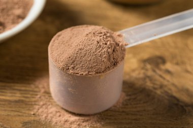 Bir kepçenin içindeki organik çikolatalı süt proteini tozu.