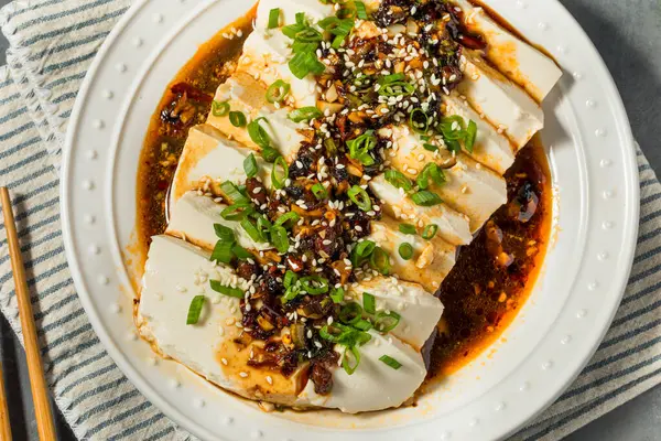 アジアのスパイシーなシルケン豆腐とチリソースと緑の玉ねぎ ストック画像