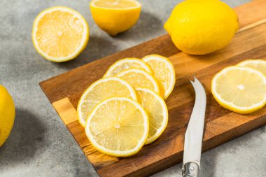 Kesme tahtasındaki organik, sarı dilimlenmiş limonlar.