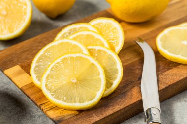 Kesme tahtasındaki organik, sarı dilimlenmiş limonlar.