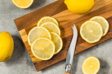 Kesme tahtasındaki organik, sarı dilimlenmiş limonlar.