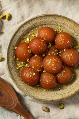 Homemade Indian Gulab Jamun Dessert in Syrup with Pistacchios clipart