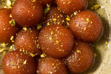 Homemade Indian Gulab Jamun Dessert in Syrup with Pistacchios clipart