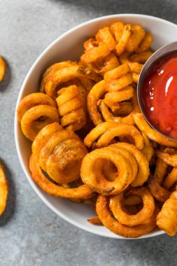 Sağlıksız, baharatlı, ketçaplı kıvırcık patates kızartması.