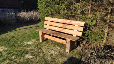 Bahçede yeşil çimlerin üzerinde yeşil çitlere karşı bankta