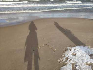 Gündüz vakti kar bulutları ve mavi gökyüzü olan kış kumsalı