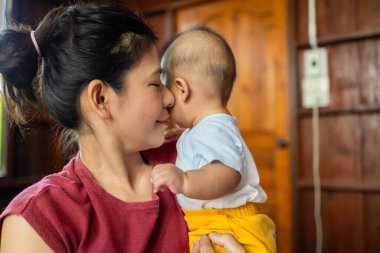 Anne ve bebek yatakta oynuyorlar. Mutlu, Asyalı bebek 4-5-6 aylık, açık havada aile kavramı.