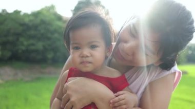 Anne ile oynayan küçük kız mutlu kucaklaşmalar, Thai asia genç anne parkta bebeği tutuyor, mutlu aile çocuğu yaşam tarzı rüya kavramı