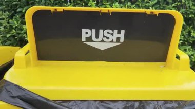 Çöp, Sarı Geri Dönüşüm Plastik Kutusu bahçede, yakın plan, Tekerlek Kutusu, Çöp ve Atık için PUSH sembolü olan çöp kutusu