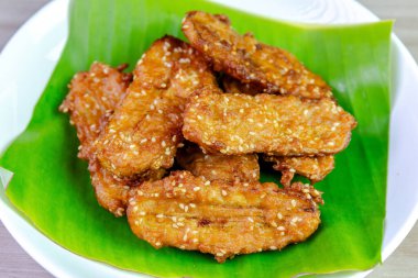 Beyaz bir tabakta muz yaprağında servis edilen kızarmış Tayland muzu, tatlı ve çıtır çıtır dokulu geleneksel Asya atıştırmalığıdır. Üst görünüm yakın çekim