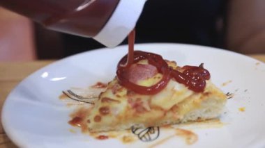 Pizzaya domates sosu dökmek, pizza bıçağı tabaktaki peynirli pizzayı kesmek, gündelik bir yemek sırasında taze pişmiş pizzanın yakın plan görüntüsü.
