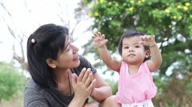 Anne ve bebek dışarıda mutlu bir şekilde oynuyorlar, sevgi gösteriyorlar, kaynaşıyorlar, mutlu anne ve bebek aktiviteleri yapıyorlar, ve doğada neşeli bir aile ortamında sıcaklık var.