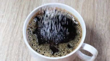 Şeker beyaz fincanda sade kahveye dökülüyor, tat, tatlılık, bağımlılık ve diyabet gibi sağlık sorunlarını gösteriyor. Reklamlar ya da sağlık konuları için mükemmel, yakın çekim