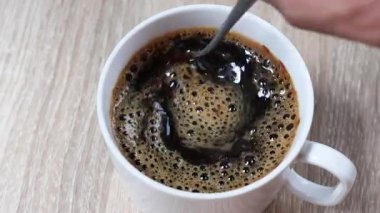 Beyaz bardakta köpüklü sade kahve karıştırmak, tazeliği, enerjiyi ve rahatlamayı çağrıştırıyor. Kafe reklamları, yaşam tarzı veya içecek içeriği için mükemmel