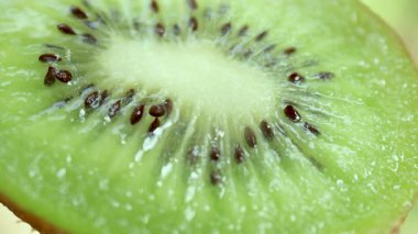 Yakın plan kivi, sulu bir kivinin makro görüntüsü tohumlarının ve dokusunun canlı detaylarını gösteriyor. Kivi besleyici ve ferahlatıcı bir meyvedir.