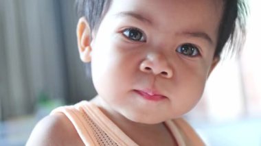 Bebek yüzlü Taylandlı küçük kızın kameraya bakarken mutlu ve eğleniyor. Çocukluk teması, duygu, masumiyet ve doğal Asya portresi için mükemmel.