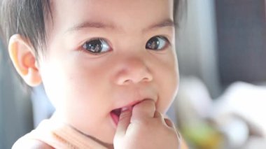 Asyalı bebek elleriyle kendini besliyor. Erken çocukluk gelişimi, bağımsızlık ve kendini besleme yeteneğinin doğal bir anı. Yakın çekim.